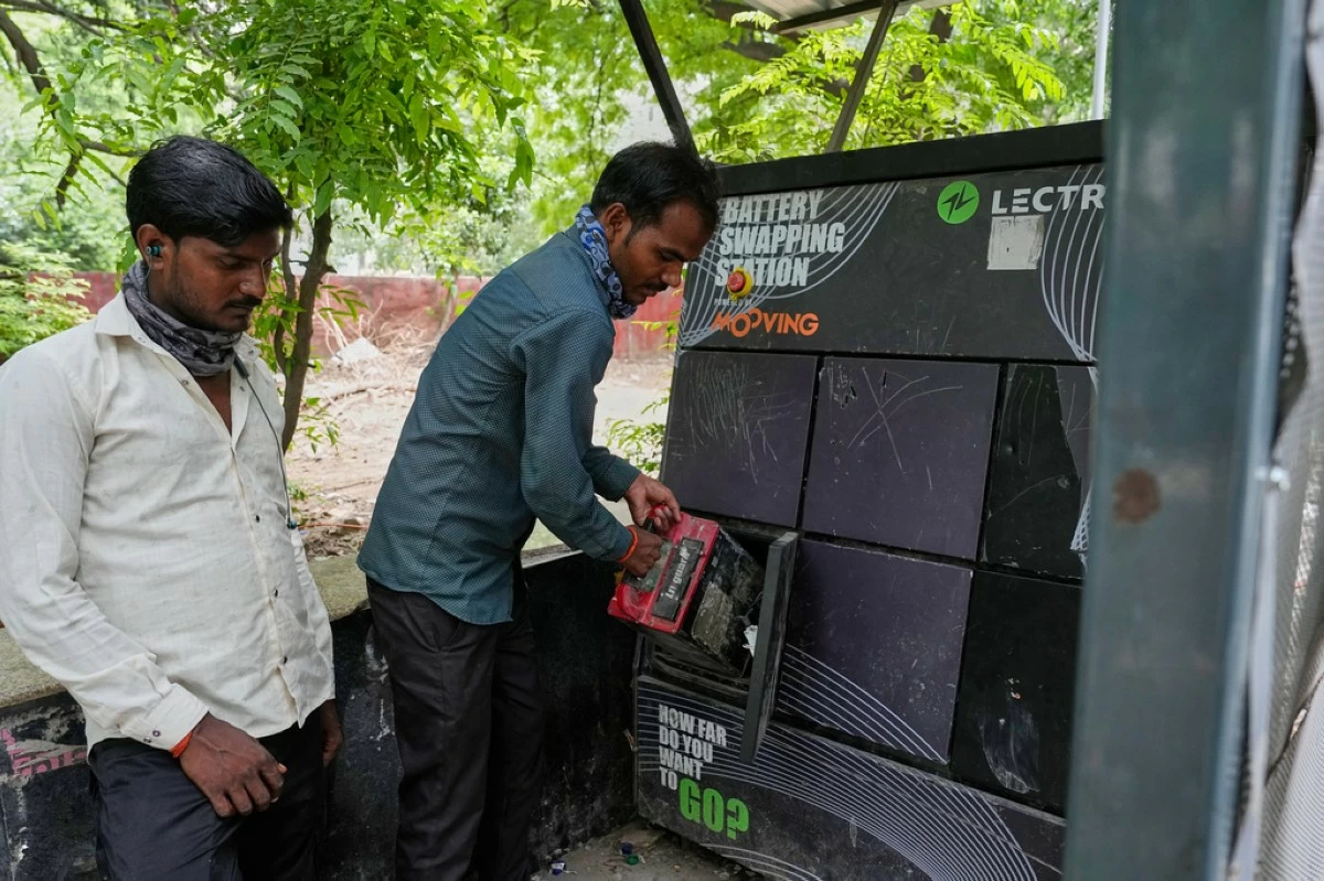 A person swaps their electric scooter battery at a battery-swapping station for electric vehicles in New Delhi, India, Monday, July 13, 2026. (AP Photo/Manish Swarup)