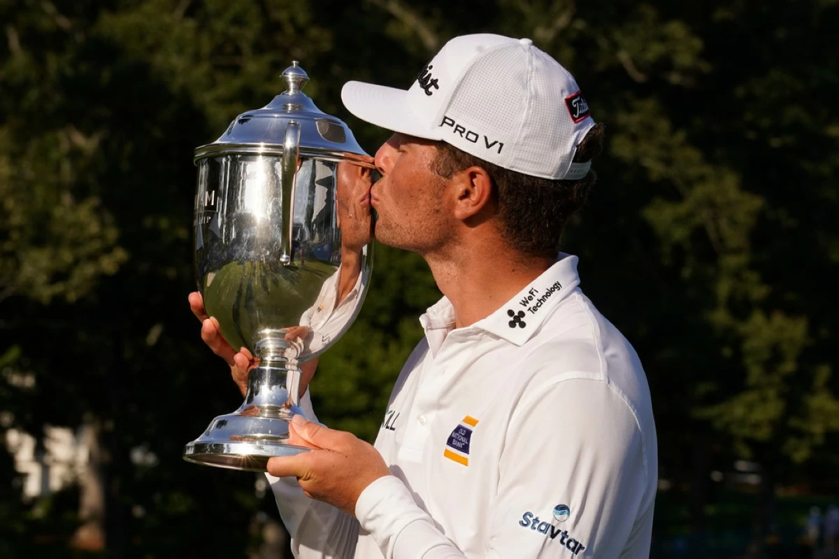 Michael Brennan kisses the trophy after winning the Wyndham Championship golf tournament in Greensboro, N.C., Sunday, Aug. 9, 2026. (AP Photo/Chuck Burton)