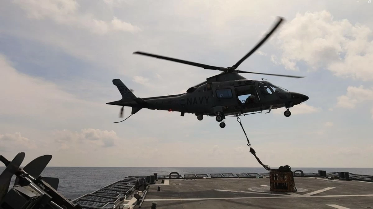 A Philippine Navy (PN) AW109 naval helicopter with tail number NH434 maneuvers to lay down a sling and net of external load during a Vertical Replenishment (VERTREP) operation involving the PN missile frigate BRP Antonio Luna (FFG15) and the United States Coast Guard Cutter Midgett (WMSL-757) in the vicinity of Bajo de Masinloc (Scarborough or Panatag Shoal) in the West Philippine Sea on May 30, 2026. (Photo: PN)