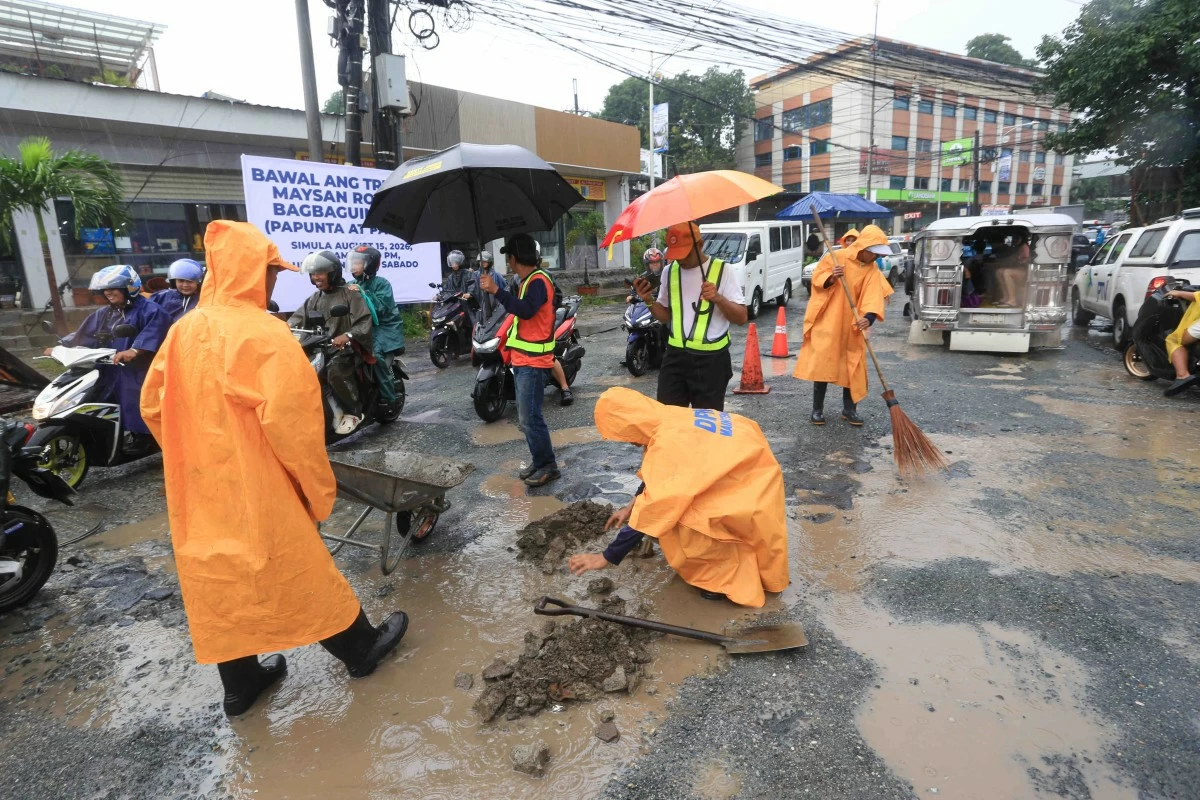 Workers from the Department of Public Works and Highways (DPWH) conduct temporary road repairs and pothole-filling operations along Maysan Road in Valenzuela City on Thursday, August 13, 2026. DPWH Secretary Vince Dizon said the road was damaged by flooding caused by continuous rains brought by the southwest monsoon. (Santi San Juan)