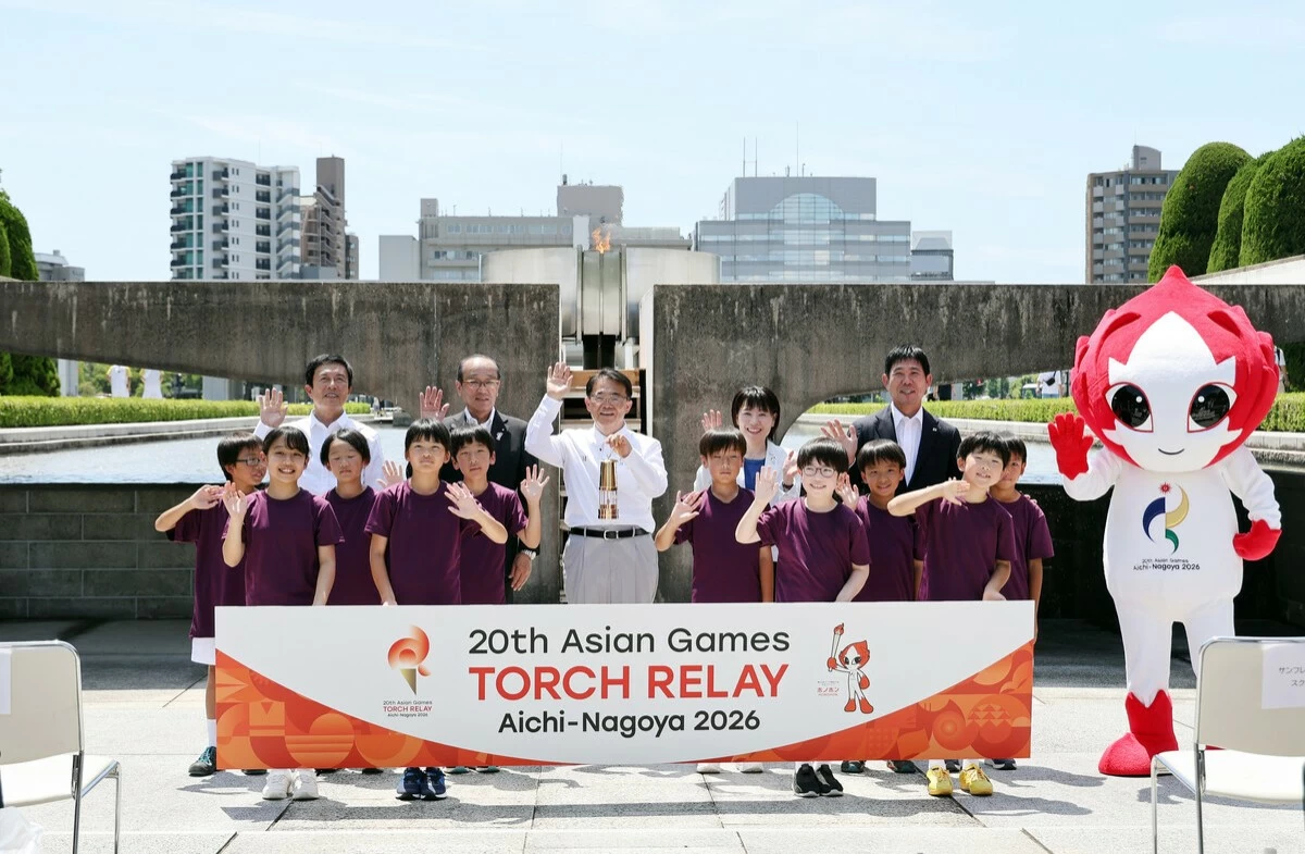 Hajime Moriyasu (far right, back), head coach of the Japanese men's national soccer team, and others pose for a photo at a flame-lighting event held at Hiroshima Peace Memorial Park on Thursday for the torch relay for the Asian Games scheduled for Sept. 19 to Oct. 4 mainly in Aichi.