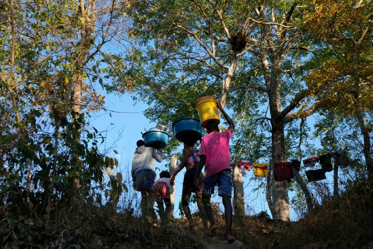 Children carry water from the Branco River at dawn at the Kalunga quilombo, a Brazilian settlement founded by escaped enslaved Africans, in the rural area of Cavalcante in Goias state, Brazil, Aug. 15, 2022. (AP Photo/Eraldo Peres, File)