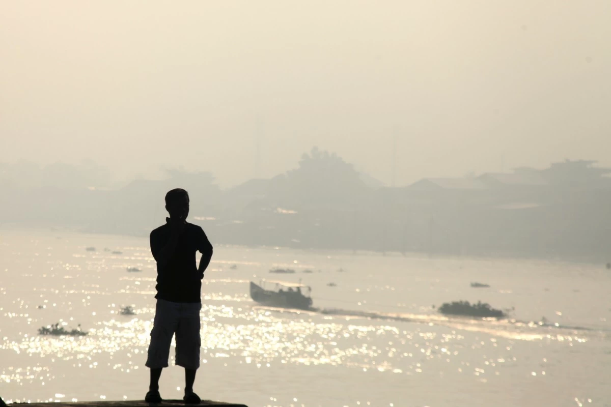 A man is silhouetted against the haze from wildfires that blankets Musi River in Palembang, South Sumatra, Indonesia, Sunday, Aug. 23, 2026. (AP Photo/Muhammad Fajri)