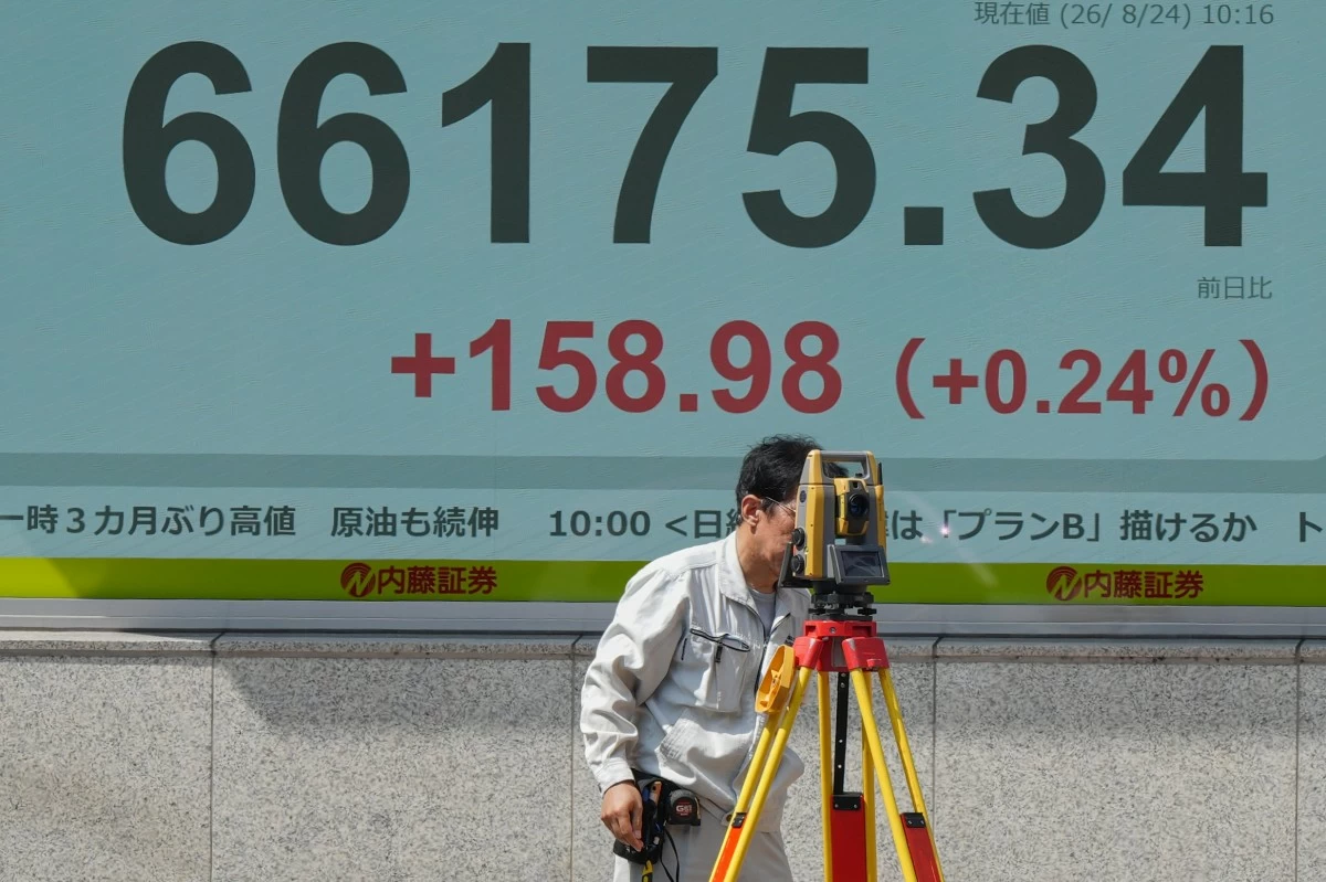 A surveyor works in front of a stock market chart Monday, Aug. 24, 2026 in Tokyo. (AP Photo/Eugene Hoshiko)