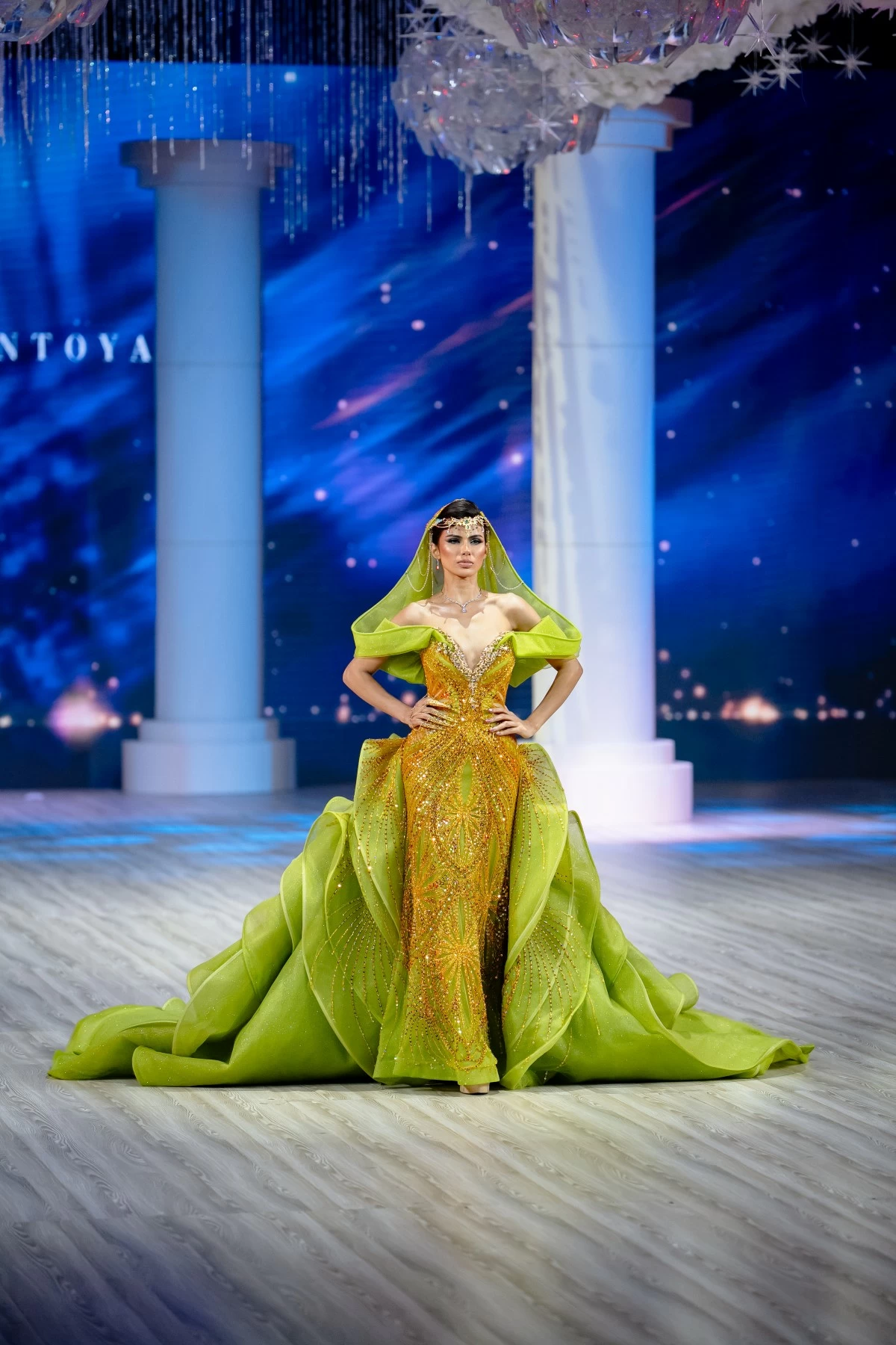 Embellished with intricate marigold beadwork, this look is completed with an off-shoulder hooded veil and a grand cascading train.
