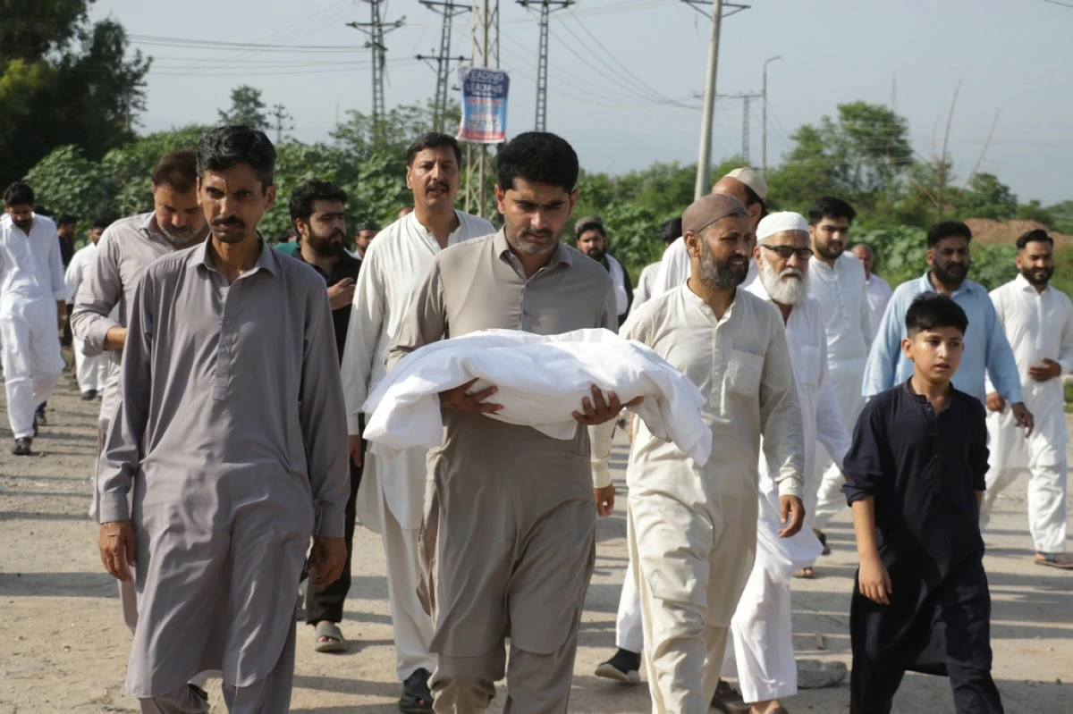 A man carries the body of a newborn for burial after the child died in a fire at a hospital in Islamabad, Pakistan, Wednesday, Aug. 26, 2026. (AP Photo/Ehsan Shahzad)