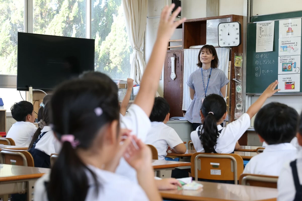 Schoolchildren raise their hands in class on Friday as the new term begins in
Yatsushiro, Kumamoto Prefecture.