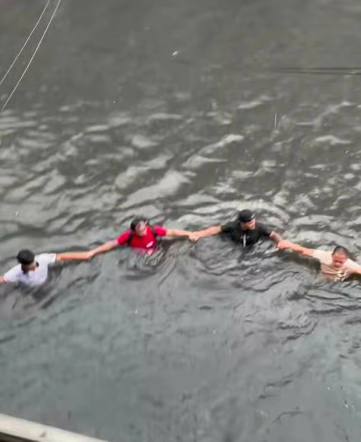 Residents form a human chain to help rescuers bring four children to safety at Paso de Blas Bridge in Valenzuela City on Saturday, Aug. 29. (Screengrab from Leng Deocareza/Facebook)