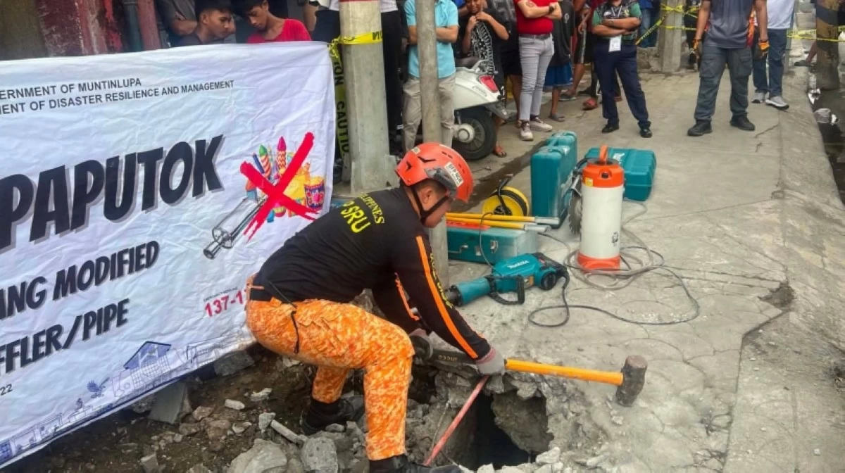 An employee of the Muntinlupa City Fire Station smashing a hole on a sidewalk in Barangay Bayanan, Muntinlupa, on Aug. 27 (Photo from BFP Muntinlupa) 