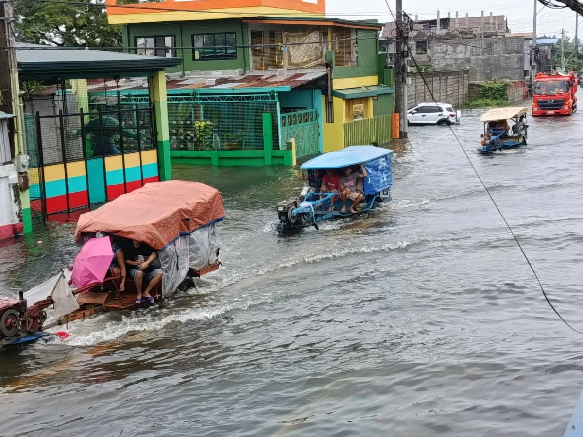 Residents in Calasiao, Pangasinan, board a kuliglig while others wade through floodwaters as the southwest monsoon continues to inundate communities.(Liezle Basa Inigo)
