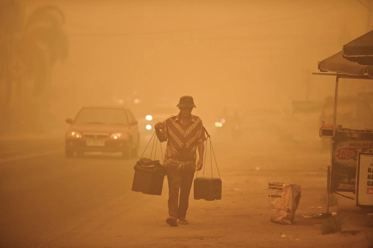 A street vendor walks amid thick haze from wildfires in Palangkaraya, Central Kalimantan, Indonesia, Saturday, Oct. 24, 2026. (AP Photo/Yulianus Stefan Lundju)