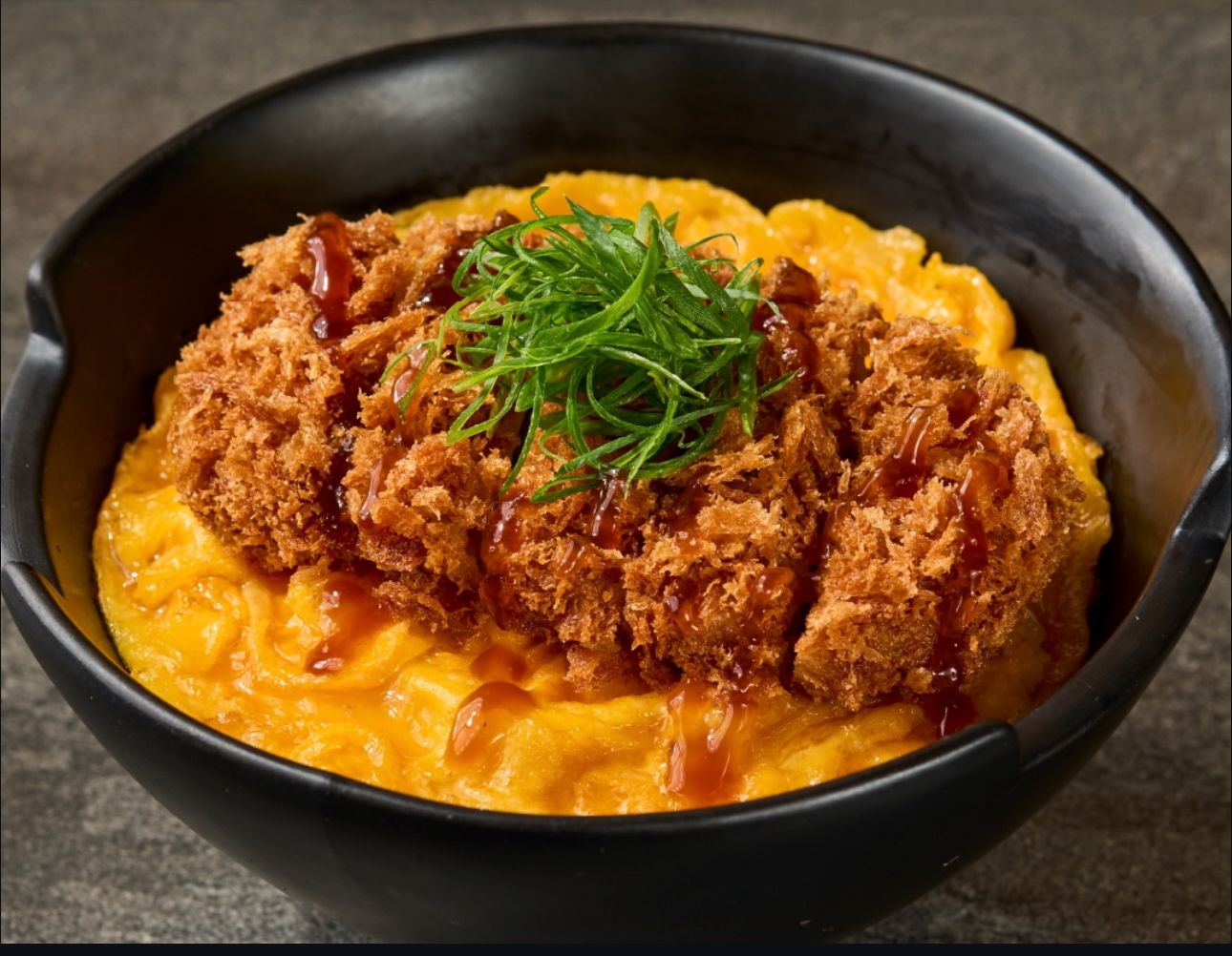 CRISPY KATSUDON Extra crunchy katsu served in a bed of the silkiest tamagoyaki omelette, Japanese rice, and rich donburi sauce.jpeg