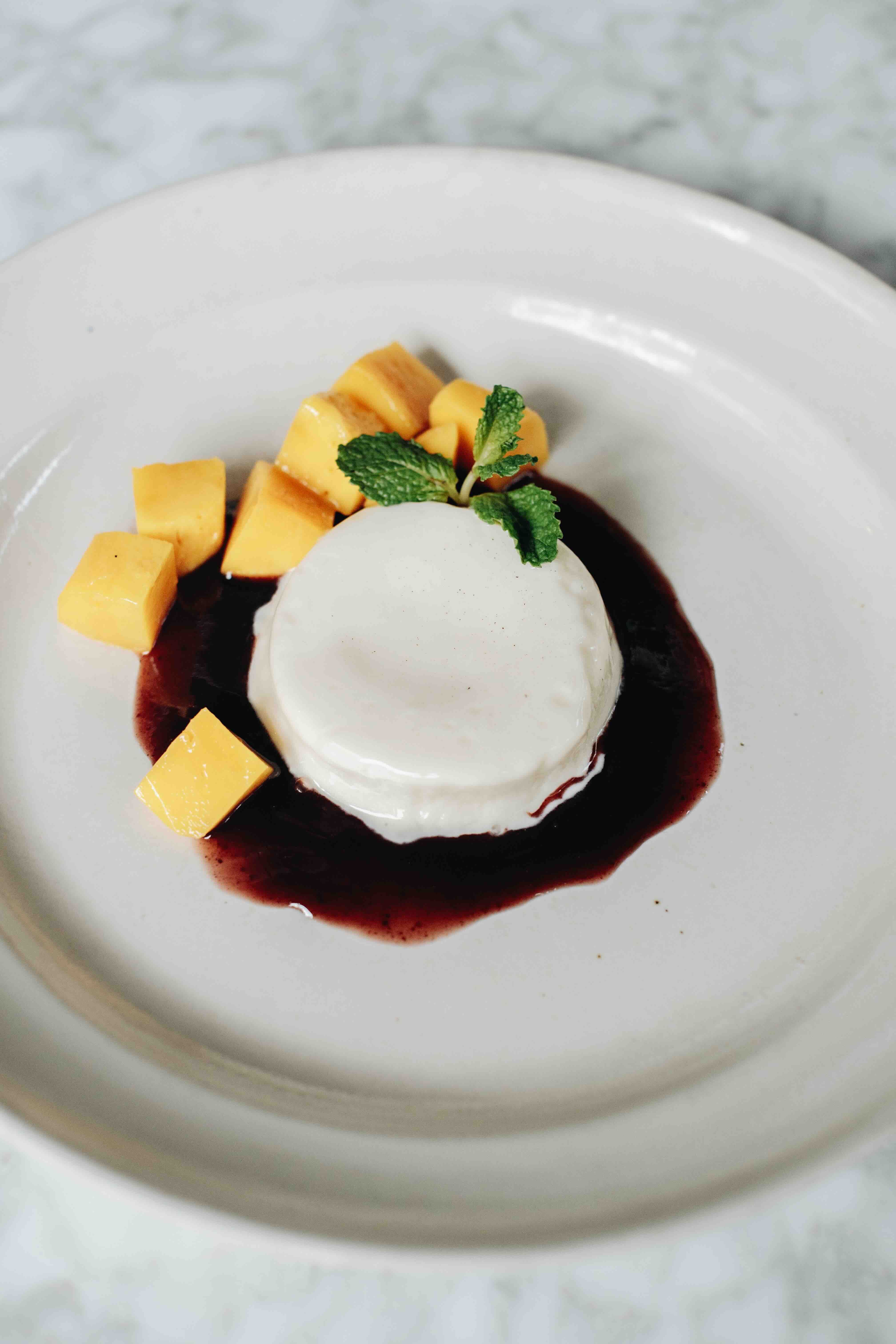 PANNA COTTA A base of organic cream and vanilla, topped with raspberry sauce, blackberry jam, and chunks of fresh golden mango.jpeg