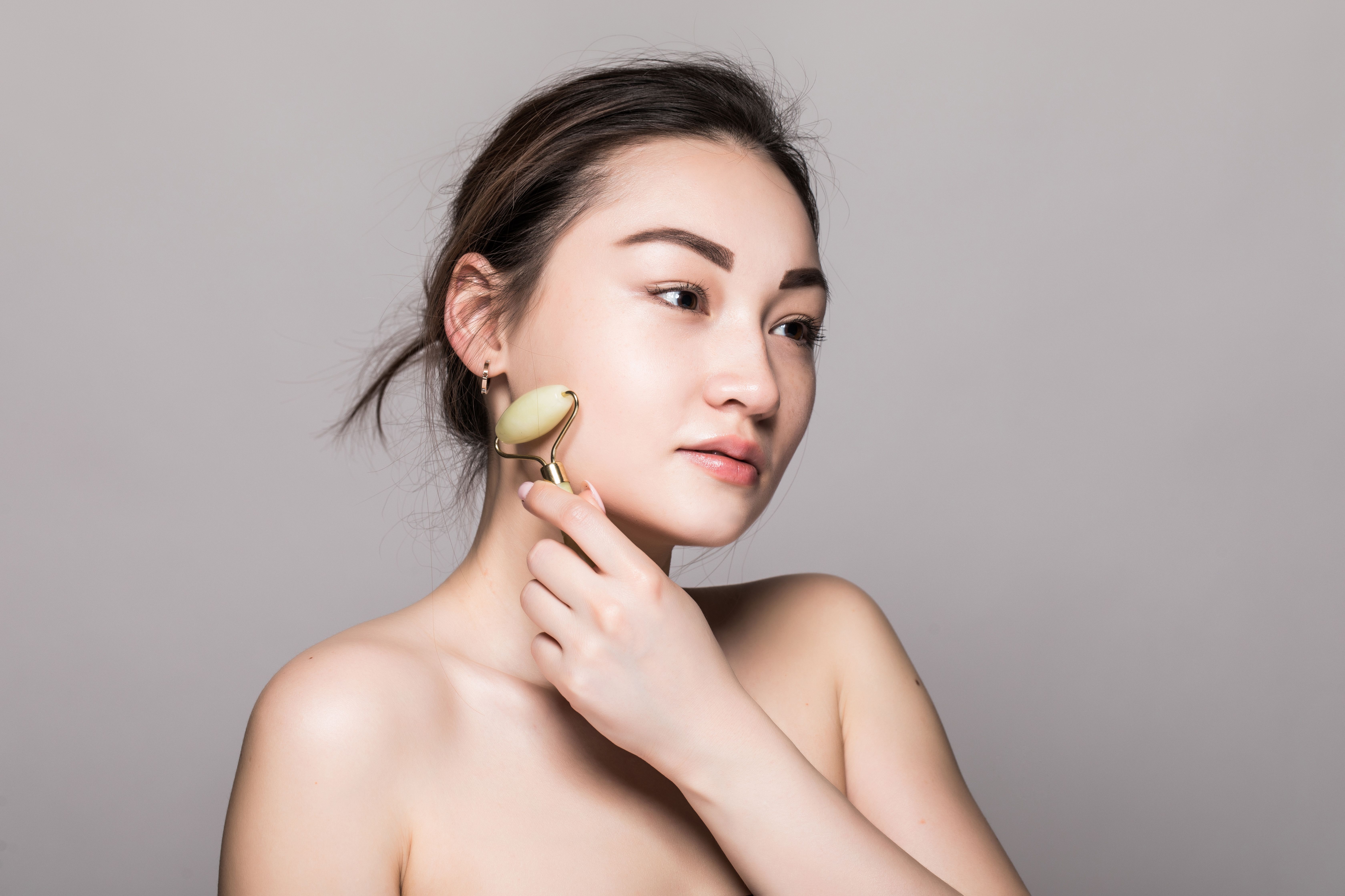 beautiful-young-asian-woman-using-jade-face-roller-her-flawless-skin-beauty-face-closeup-conceptual-facial-treatments-with-semi-precious-stones-isolated-gray-with-copy-space.jpg